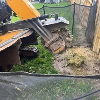 Stump grinder grinding a low stump along a fence line in Greenwood, Indiana