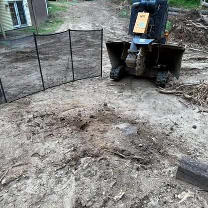Protective fence panels set up around a stump grinding job near a home